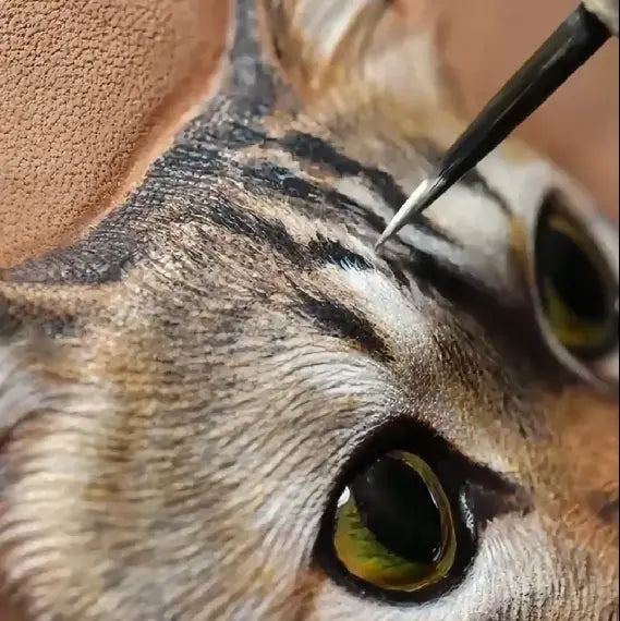 Painting the fine markings of a cat portrait on leather