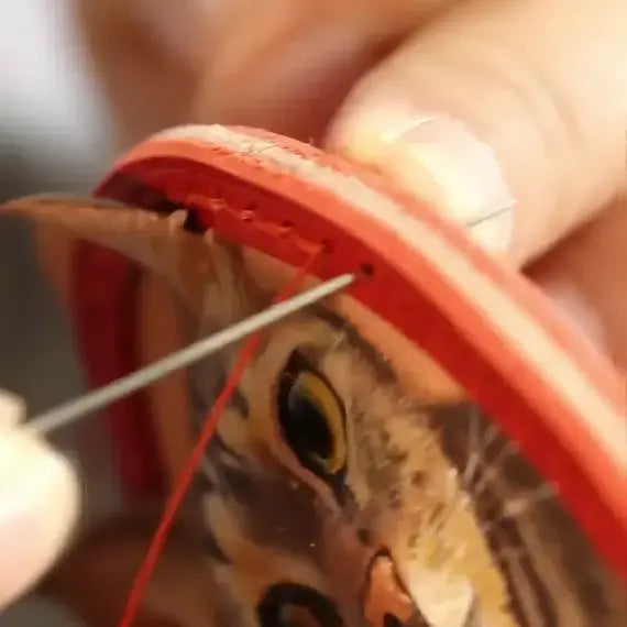 Hand stitching a leather pet portrait to its frame