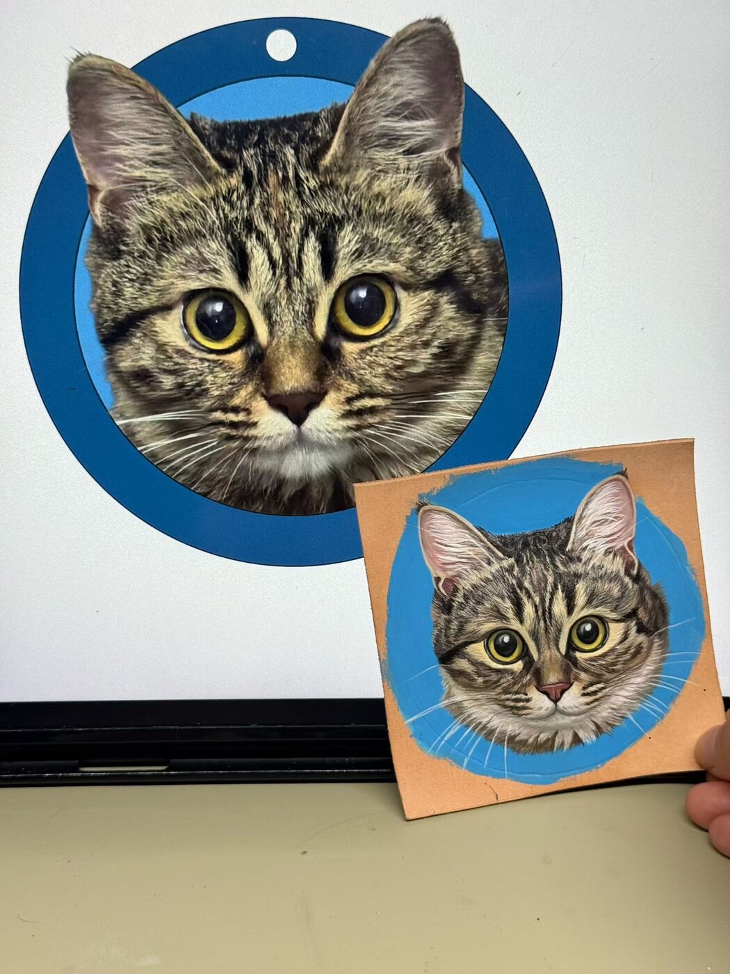 Tabby cat reference photo beside its hand-painted leather portrait